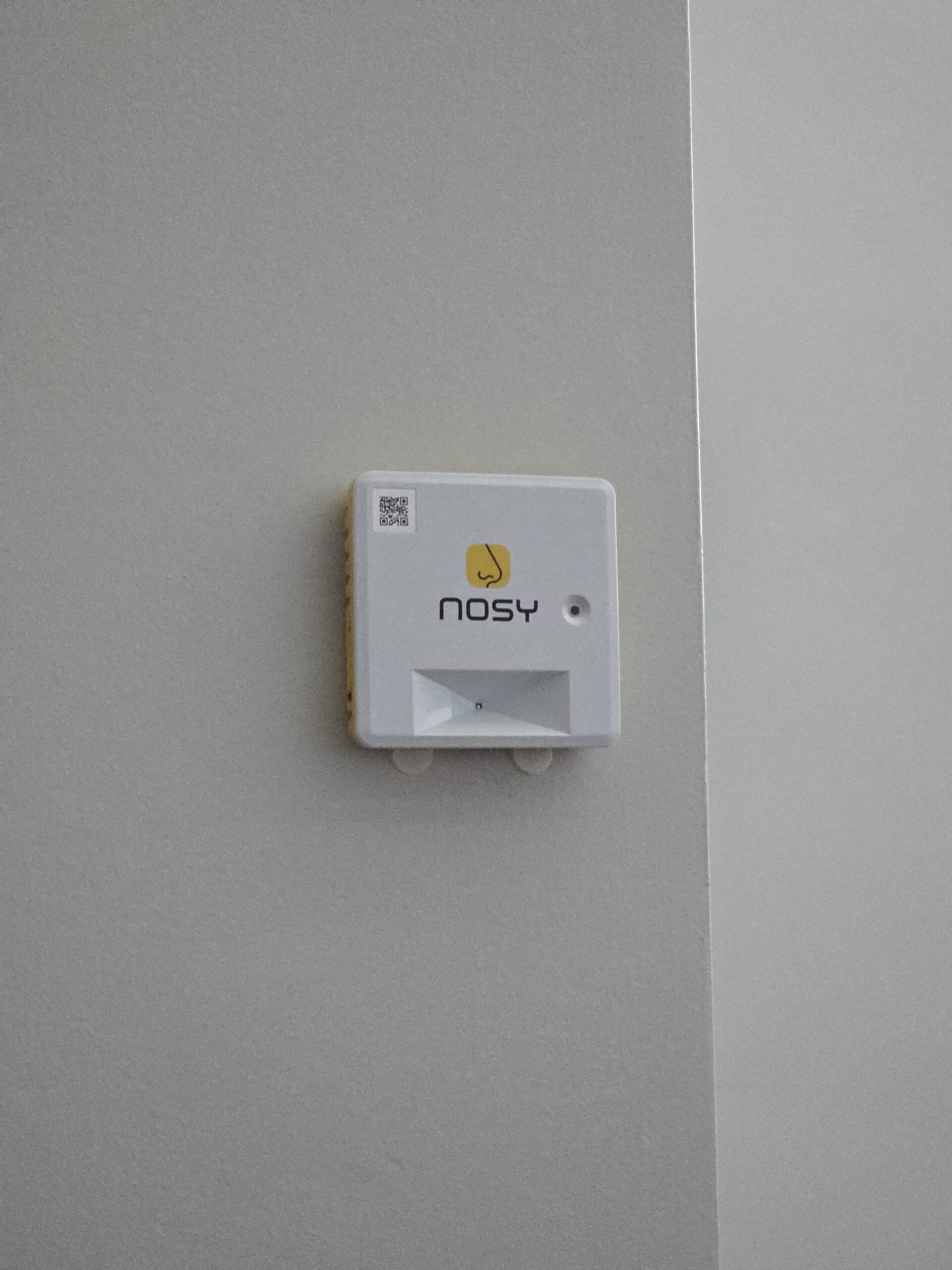 A Nosy sensor mounted on a gray wall